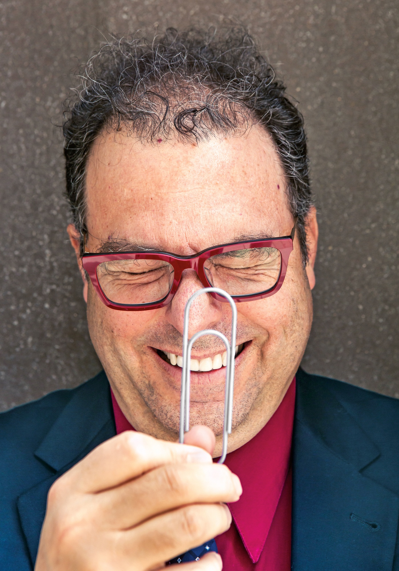 portrait of Michael Littman holding a paper clip and laughing